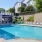 a swimming pool with chairs and a building in the background