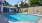 a swimming pool with chairs and a building in the background